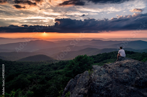 A hiker enjoying a Summer sunset from Bearfence Mountain in Shenandoah National Park.