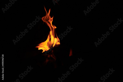 Bright vivid orange and yellow tongues of flame on black background. Burning bonfire at night. Sport tourism in summer.