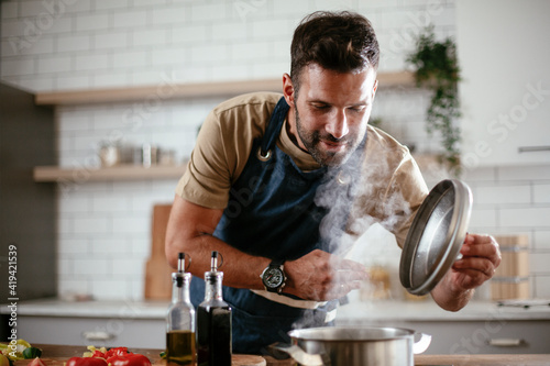 Handsome man preparing pasta in the kitchen. Guy cooking a tasty meal..