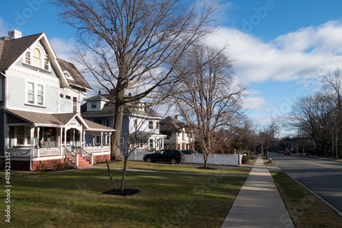 street and sidewalk of suburban homes with leafless late fall winter season trees