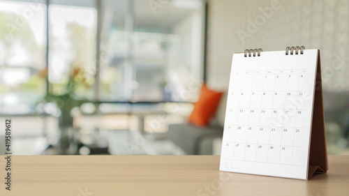 white paper desk calendar on wood table with blurred bokeh background appointment and business meeting concept