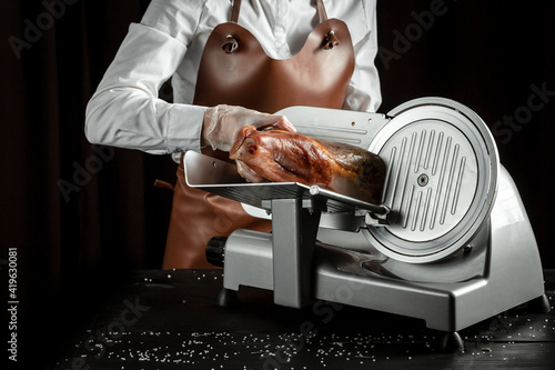 Dry Spanish ham on cutting machine, Iberian ham cutter on black background