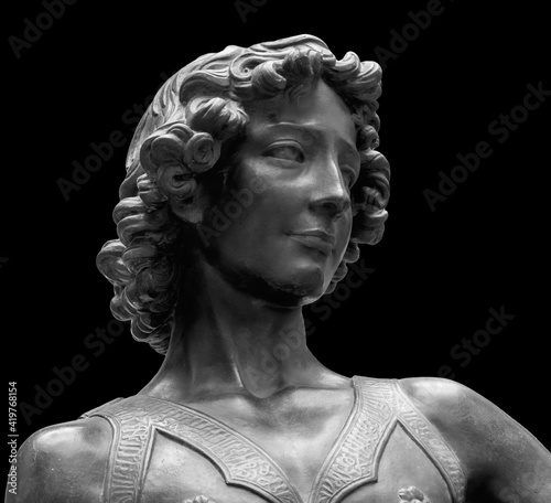 David killer of Goliath ancient statue. Biblical story. Antique sculpture of young man in armor isolated on black background