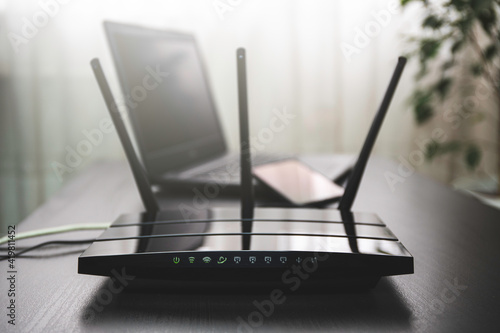WIFI router connected to the internet on table and laptop in the background