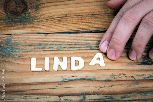 LINDA. Name of women and girls. White letters of the alphabet on a wooden background