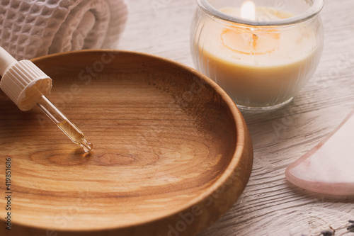 aromatic massage oil in a wooden bowl with candles