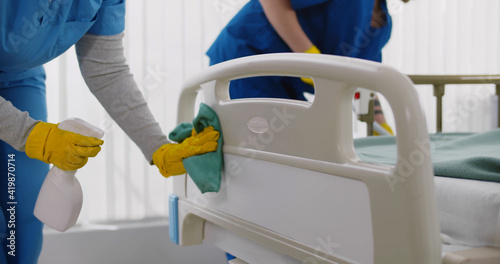 Team of professional janitors using equipment disinfecting hospital ward