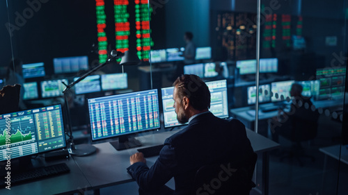 Professional Financial Data Analysts Working in a Modern Monitoring Office with Live Analytics Feed on a Big Digital Screen. Monitoring Room with Finance Specialists Sit in Front of Computers. 