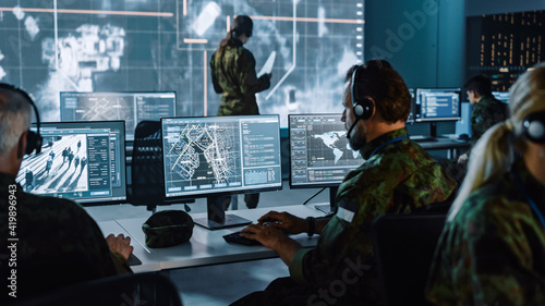 Military Surveillance Officer Working on a City Tracking Operation in a Central Office Hub for Cyber Control and Monitoring for Managing National Security, Technology and Army Communications.