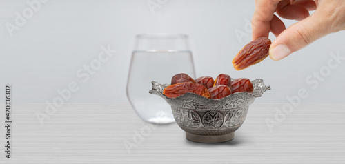 Typical of the month of Ramadan for muslims is the setting here, after the fast has been broken - water and pitted dates. Traditional iftar food. metal bowl full of date fruits symbolizing Ramadan