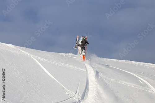 elite snowmobiler makes turns in the air on the heel of a caterpillar. snowmobilers sports riding. bright skidoo motorbike and suit without brands. snowmobile fun