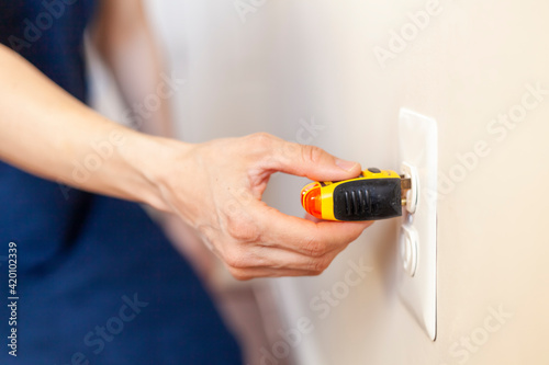 Electrical outlet tester also known as plug tester is a small device that is used to confirm proper wiring and electric current in a plug. Two yellow lights indicate active plug. Hand inserting device