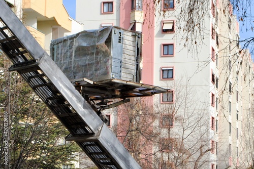 House removal with hydraulic ladder truck. Moving lift carrying furniture up at a residential area. Selective focus.