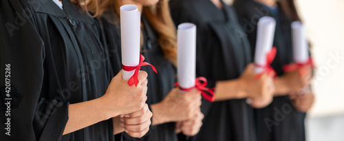 group of graduates Asian student in academic gown and graduation holding diploma certificates