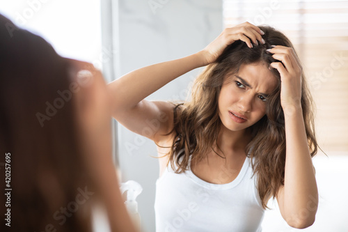 Unhappy Woman Looking At Hair Flakes Having Dandruff Problem Indoor