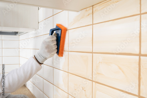 a ceramic tile laying master wipes the seams with a special sponge