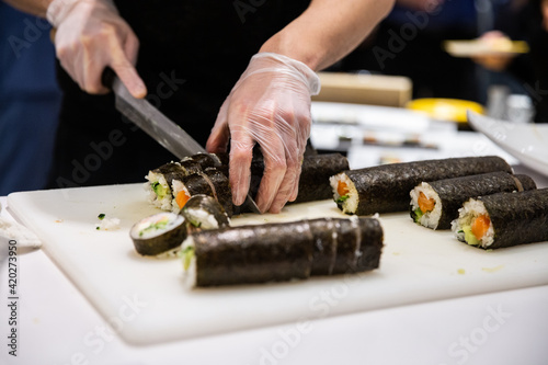 Chef en train de couper des morceaux de sushis dans un rouleau