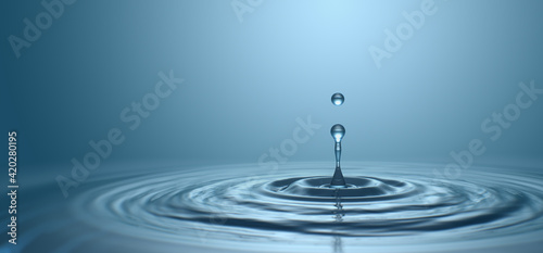 Water drop with droplet and rings on surface bluish background