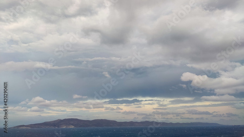 Stormy grey epic cloudscape on greek sea near rocky shore. Summer dramatic scenic view on Aegean sea in Greece