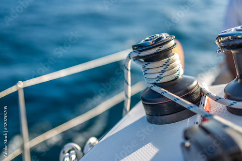 Closeup details of sailing winch equipment on a boat when sailing on the water in a sunny day. Sailboat sailing template in blue ocean sea
