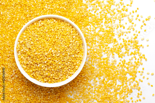 Close up of Organic yellow Gram (Vigna radiata) or split yellow moong dal on a ceramic white bowl with the gradient background of split yellow moong dal. Top view