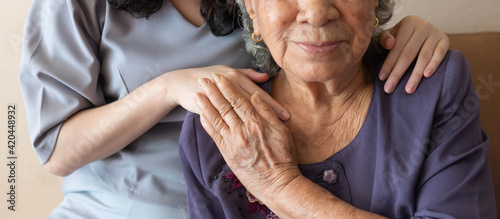 Friendly relationship between caregiver and happy eldery woman during nursing at home. Senior services and geriatric care concept.