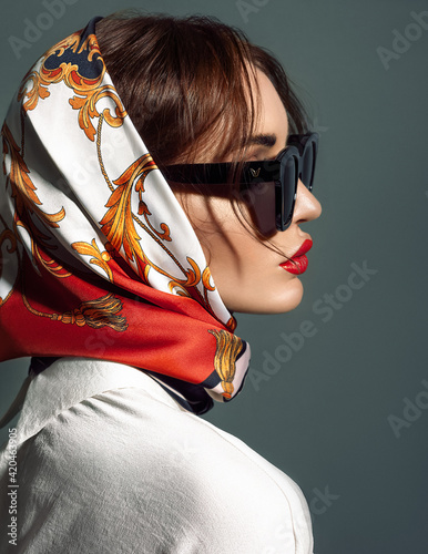 glamorous woman in black sunglasses with red lips and head scarf