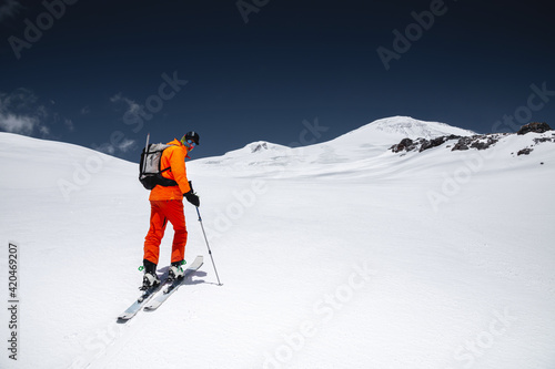 Portrait of a young male athlete skier in a ski tour on skis on the background of snow-capped mountains on a sunny day. Skitour professional