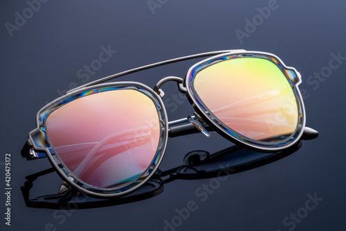 rainbow mirrored sunglasses on dark background, copy space