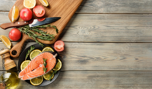 Salmon steak with ingredients for cooking on a wooden table with copy space.