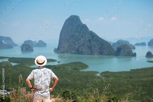 Happy traveler man enjoy Phang Nga bay view point, alone Tourist standing and relaxing at Samet Nang She, near Phuket in Southern Thailand. Southeast Asia travel, trip and summer vacation concept