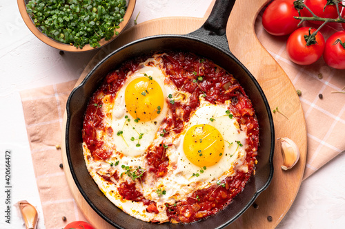 Flat lay image of shakshouka in a pan on a light coloured background