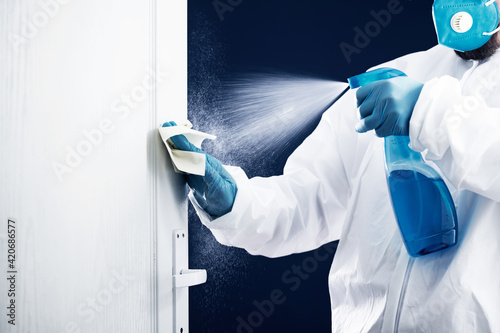 Coronavirus COVID-19 prevention. Man wiping doorknob with antibacterial disinfecting wipe for killing coronavirus.