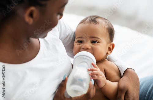 African American woman feeding her child from baby bottle