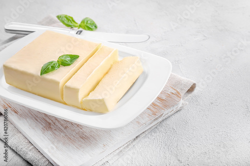 Cut block of fresh butter in white ceramic butter dish