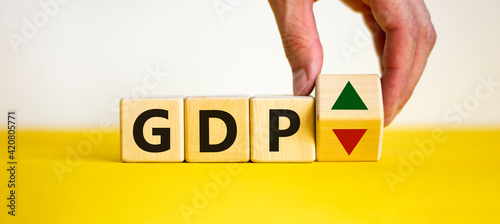 GDP, gross domestic product symbol. Businessman holds a cube with up and down icon. Word 'GDP'. Beautiful white background. Copy space. Business and growth of GDP, gross domestic product concept.