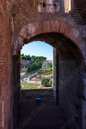 Vista del foro romano y palatino desde el coliseo, a través de uno de los arcos. Turistas paseando