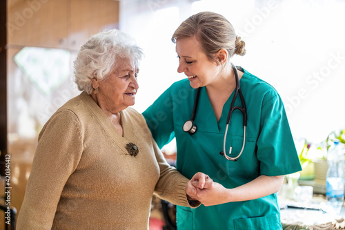 Friendly nurse supporting an elderly lady 