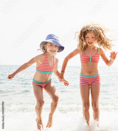 Two sisters in matching bikinis splashing in sea, Portoferraio, Tuscany, Italy