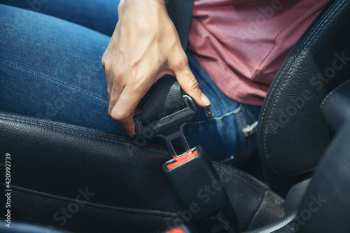 woman hand fastening a seatbelt in the car, Cropped image of a woman sitting in car and putting on her seat belt, Safe driving concept.