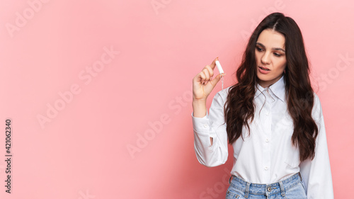 A studio shot of a girl holding a tampon in her hand in a menstrual applicator. Space for the text. The concept of feminine hygiene.