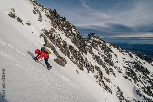 An alpinist climbing in winter alpine like landscape of High Tatras, Slovakia. Winter mountaineering in snow, ice and rock. Alpinism, high peaks and summits with snow and ice.