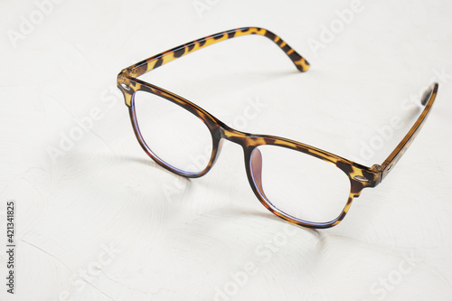 Leopard-colored trendy eyeglass frames on beige background.