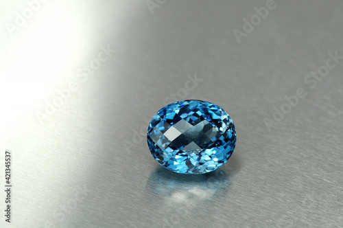 Natural swiss blue topaz. Oval cut, checkers faceted, loupe clean - VVS,IF,FL. Heated, treated, irradiated, color enhanced. Full of sparkle semiprecious gemstone in satin polished Aluminum background