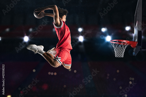 Basketball player in red uniform jumping high to make a slam dunk to the basket