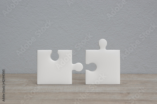 Connecting couple jigsaw puzzle on wooden table over white wall background, Business teamwork or partnership concept