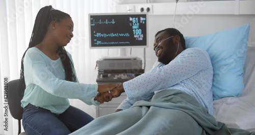 Loving and caring young african woman visiting and talking to hospitalized husband