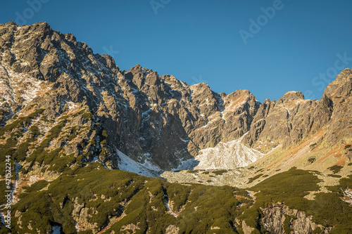 The peaks of High Tatras in the sunlight. The mountain range where the most dangerous path - Orla Perć - is located. Selective focus on the rocks, blurred background.