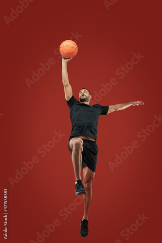 Adult bearded male in black sportswear playing in basketball in sport center