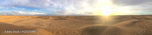Majestic panorama of landscape in the Sahara desert, Tunisia. Sun with bright rays over the desert horizon. Sand dunes against a beautiful sky